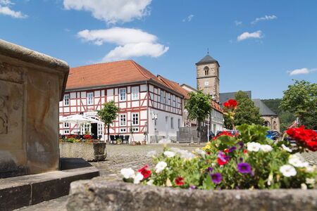 Marktplatz in Creuzburg mit Blumendetail und Fachwerkhaus. Im Hintergrund ist die Kirche zu sehen.